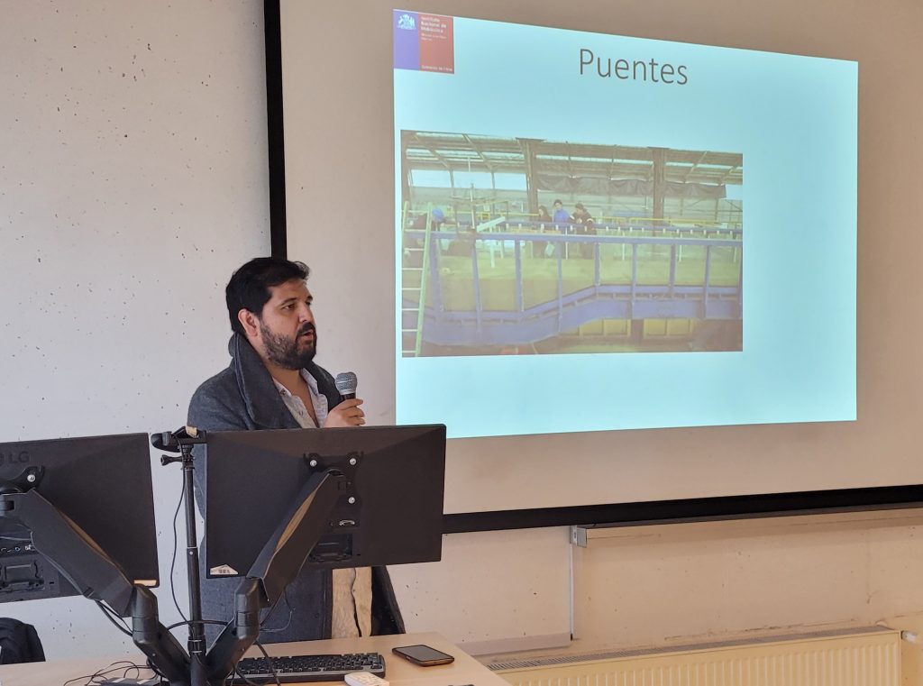 Jaime Cotroneo exponiendo, con una lámina de su presentación, con el texto Puentes y una imagen del Canal de Socavación del Pilas del INH.