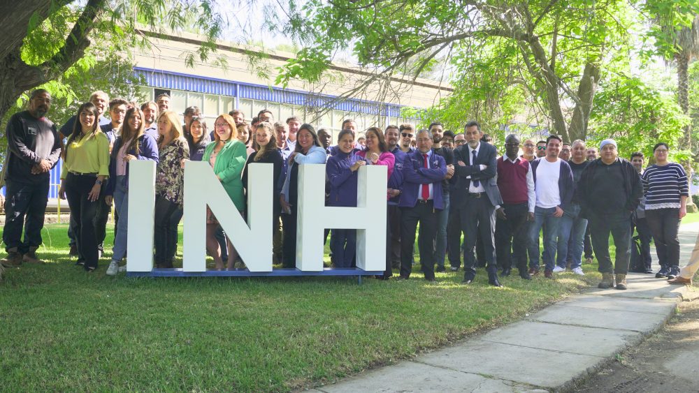 Equipo INH de pie junto a las letras volumétricas "INH".