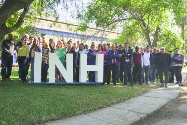 Equipo INH de pie junto a las letras volumétricas "INH".